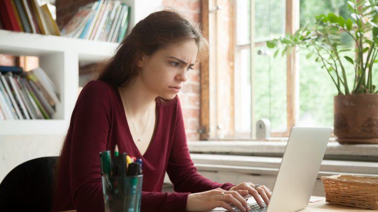 Junge Frau sitzt nervös vor ihrem Computer