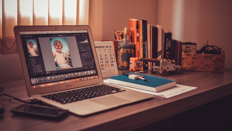 Photoshop auf einem Macbook Air auf einem Tisch mit Schreibtischutensilien