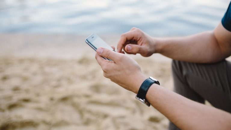 Mann nutzt iPhone am Strand