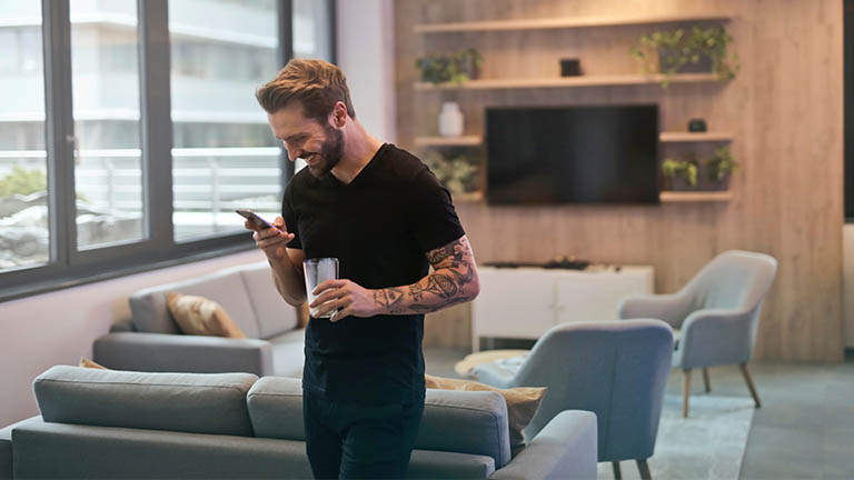 Mann mit Smartphone in Wohnzimmer