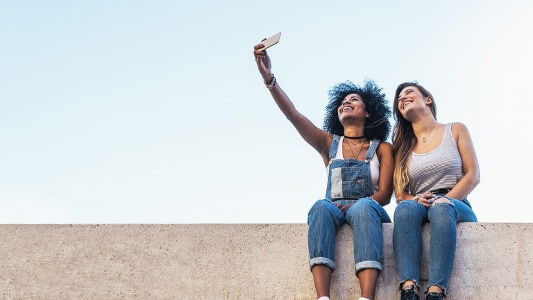 Zwei junge Frauen machen Selfie mit dem iPhone und wollen es per Mail-Anhang versenden