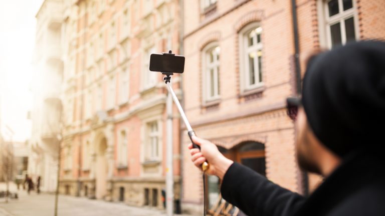 Selfies in einer schönen Straße mit Altbauten mit Selfie-Stick machen
