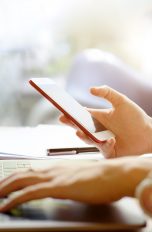 Zwei-Faktor-Authentifizierung bei Google einrichten Person sitzt am Tisch und schaut aufs Smartphone