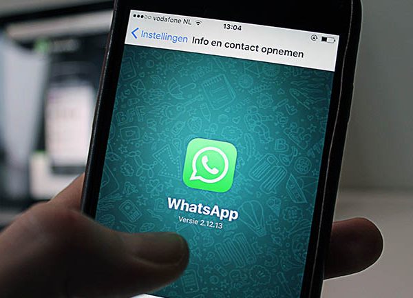 WhatsApp-Logo, davor zwei H&auml;nde mit Smartphones