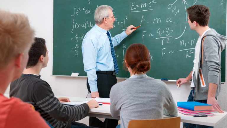 Schüler im Matheunterricht lösen Aufgabe an der Tafel Schüler im Matheunterricht lösen Aufgabe an der Tafel