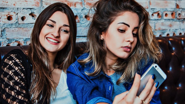 Zwei junge Frauen machen Selfies mit einem iPhone