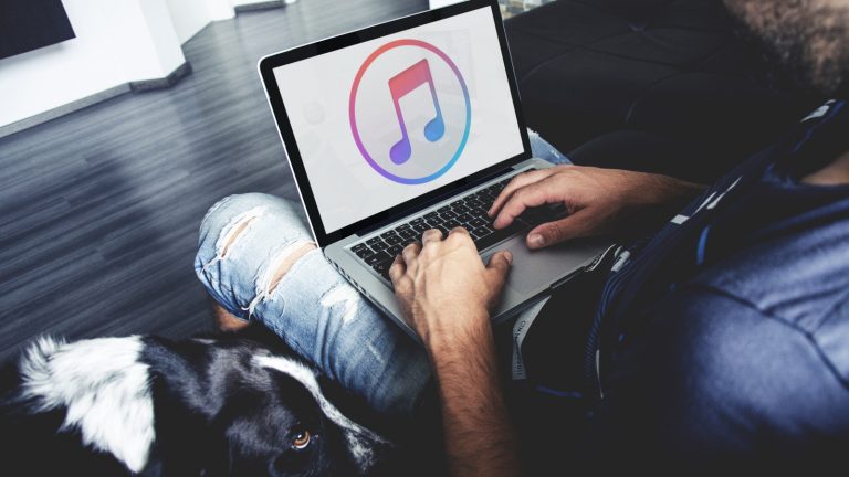 Junger Mann öffnet iTunes nach dem Back-up auf seinem MacBook Junger Mann öffnet iTunes nach dem Back-up auf seinem MacBook
