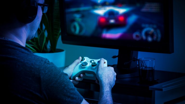 Mann spielt am PC mit einem Xbox-Controller ein Rennauto-Spiel