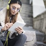 Junges M&auml;dchen erg&auml;nzt auf Tablet Songs f&uuml;r gemeinsame Spotify-Playlist
