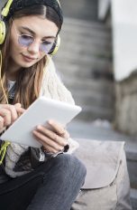 Junges Mädchen ergänzt auf Tablet Songs für gemeinsame Spotify-Playlist