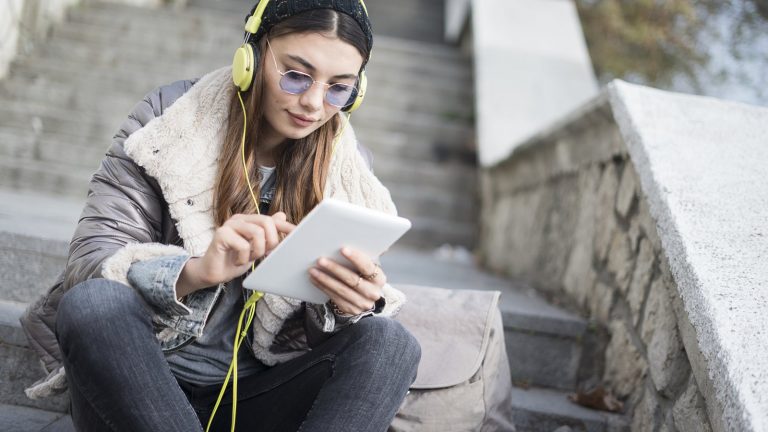 Junges Mädchen ergänzt auf Tablet Songs für gemeinsame Spotify-Playlist