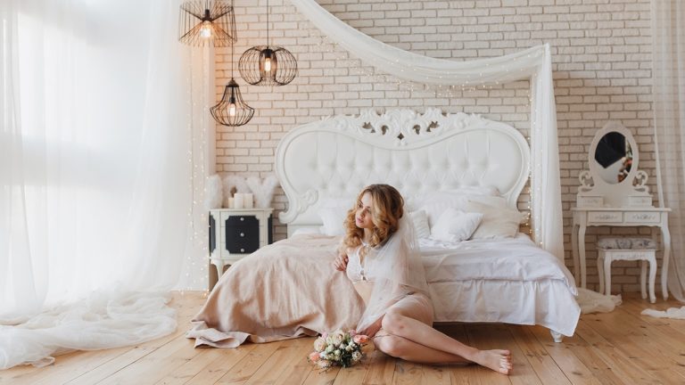 Frau bei einem Boudoir-Shooting in einem hellen Zimmer mit wei&szlig;em Himmelbett