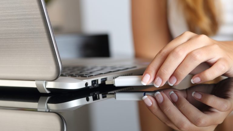 Hand zieht USB-Stick vom Laptop ab Hand zieht USB-Stick vom Laptop ab