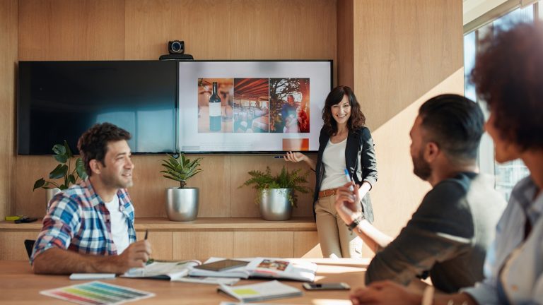 PowerPoint Endlosschleife: Frau steht vor einer Präsentation und lächelt