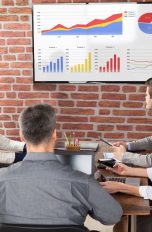 Wasserzeichen in PowerPoint einfügen PowerPoint Wasserzeichen einfügen: Frau steht vor Präsentation und zeigt darauf