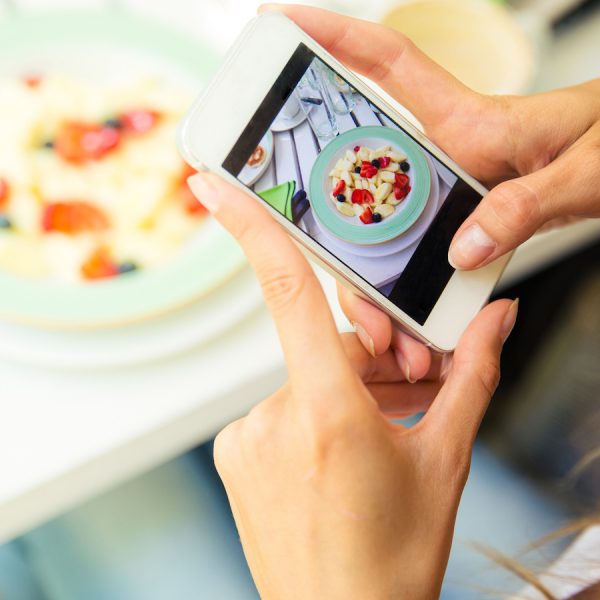 Instagram-Daten schützen: Junge Frau fotografiert ihr Essen mit dem Smartphone