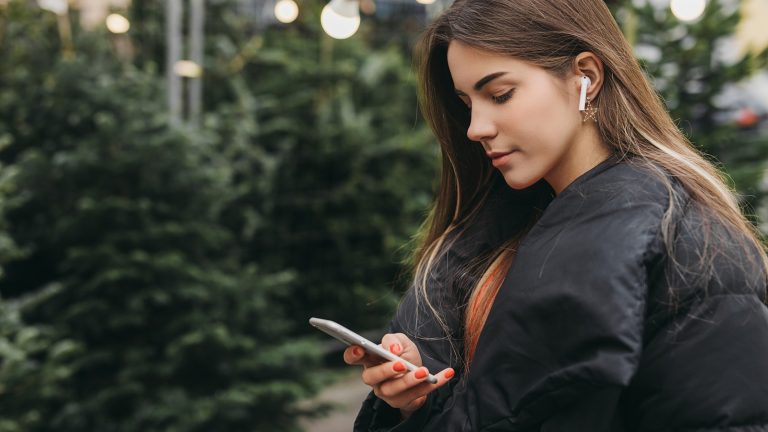 Frau hört Musik mit iPhone und AirPods