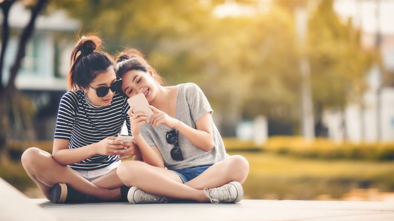Zwei Freundinnen schauen gemeinsam auf einen Android-Split-Screen