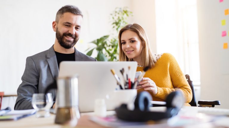 Zwei Geschäftspartner sitzen an einem Laptop und teilen sich den Bildschirm