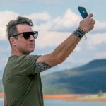 Mann vor Naturkulisse knipst Selfie mit Smartphone