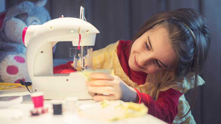 Mädchen an Nähmaschine für Kinde