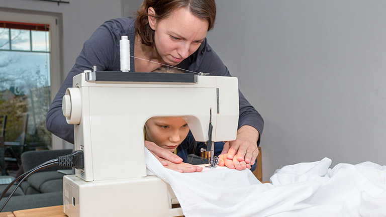Nähmaschine für Kinder: Darauf solltest du achten Mutter zeigt Mädchen das Nähen an der Nähmaschine