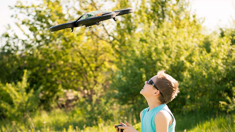 Kind steuert draußen in der Natur eine Drohne