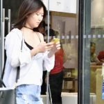 Frau vor Huawei Store mit Smartphone in der Hand