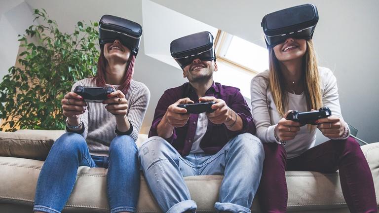 Drei junge Leute mit PlayStation-Controllern und VR-Headsets