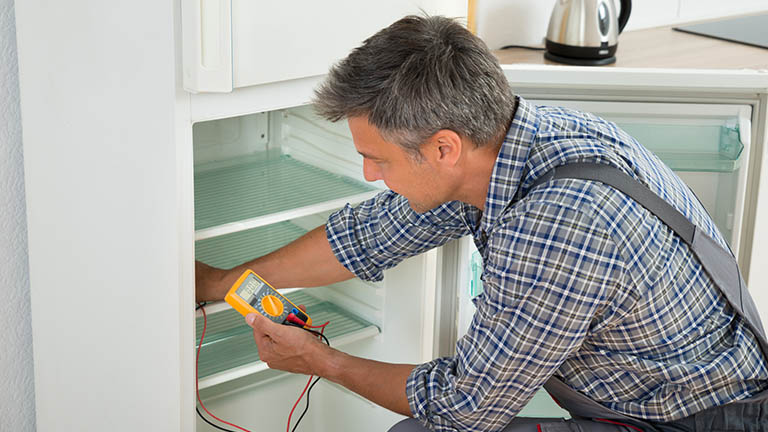 Ein Techniker testet den Thermostat eines Kühlschranks im Gerät