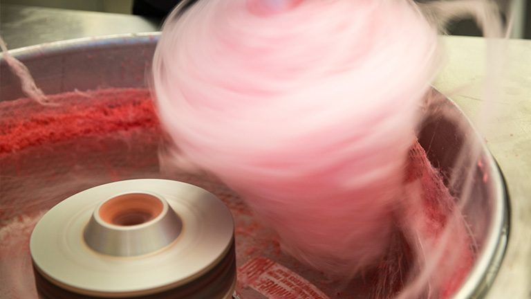 Rosafarbene Zuckerwatte wird in einer Zuckerwattemaschine aufgewickelt