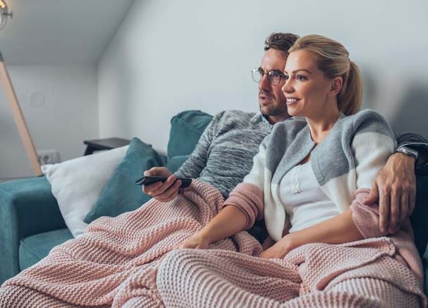 Paar sitzt auf der Couch und schaut Fernsehen &uuml;bers Internet