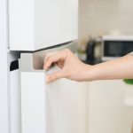 Hand öffnet Kühlschranktür