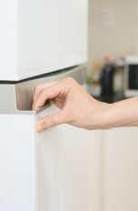 Hand öffnet Kühlschranktür