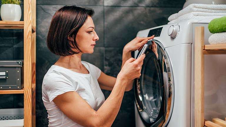 Frau programmiert smarte Waschmaschine