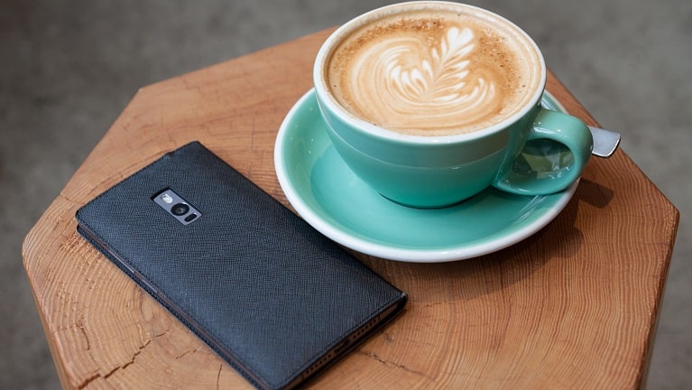 Ein OnePlus-Smartphone neben einer Kaffeetasse
