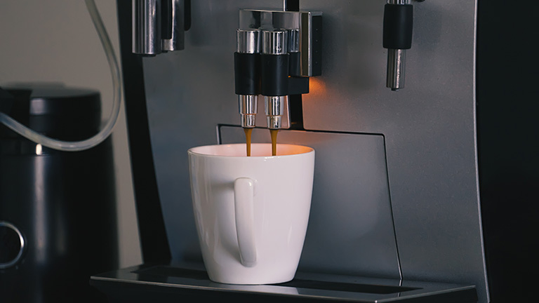 Eine Tasse wird durch eine Kaffeemaschine gefüllt