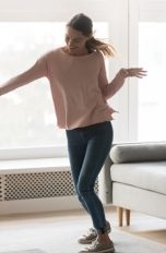 Eine Frau tanzt zu Musik aus ihrem Sonos-Lautsprecher im Wohnzimmer