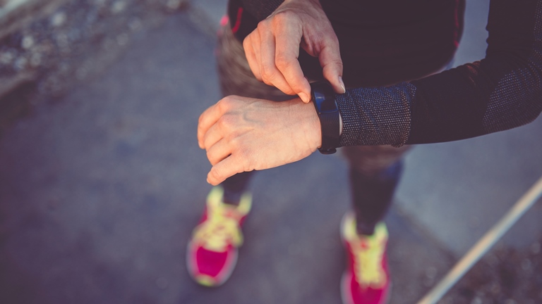 Frau schaut auf Fitness-Tracker