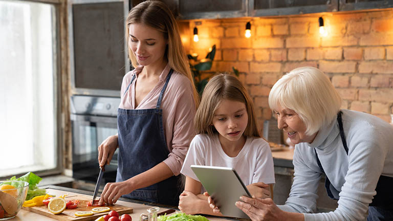 Eine Familie kocht mithilfe eines virtuellen Rezepts auf dem Smart Display