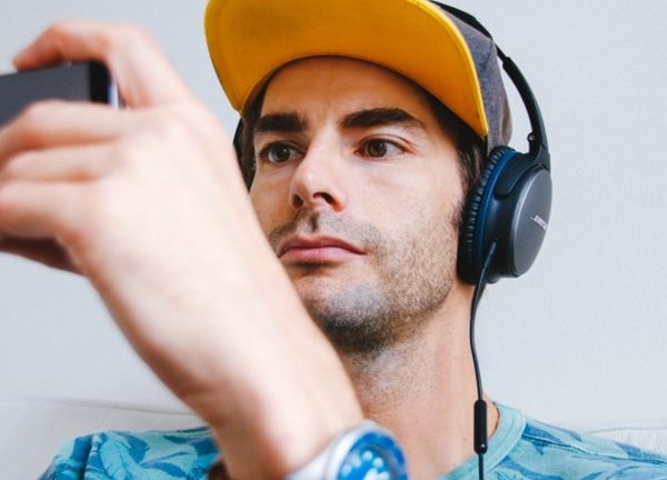 Mann mit Kopfh&ouml;rern h&auml;lt Smartphone