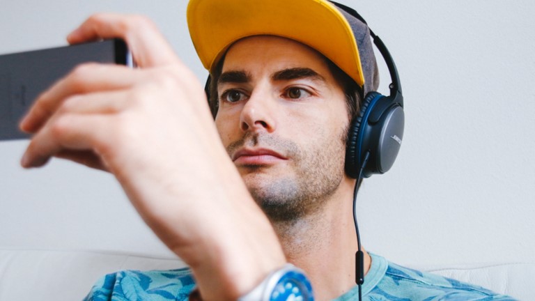 Mann mit Kopfh&ouml;rern h&auml;lt Smartphone
