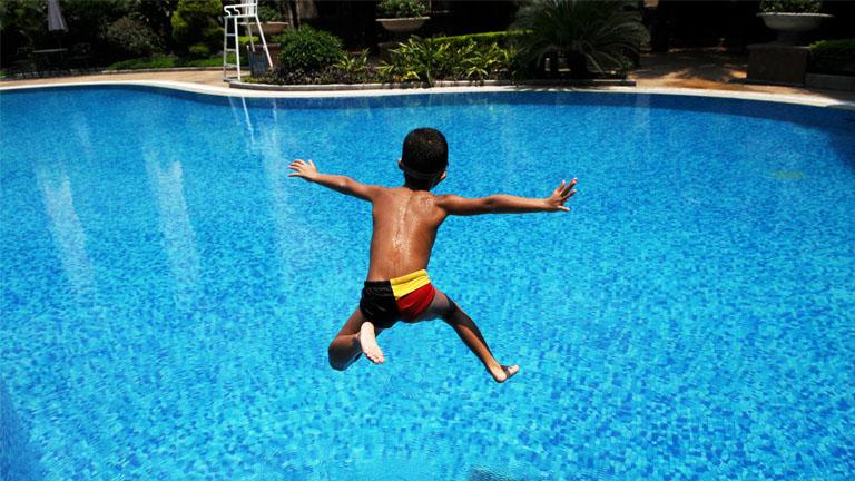 Ein Junge springt in den Pool