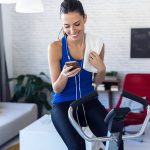 Frau trainiert zu Hause auf Fitnessgerät