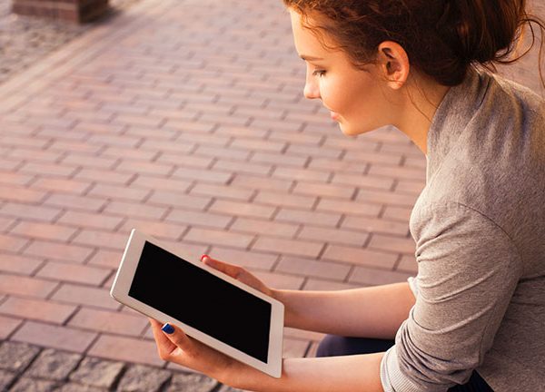 Frau tippt lächelnd auf Tablet