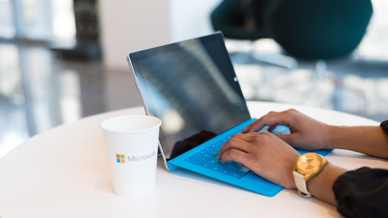 Frauenhände tippen auf einem blauen Laptop