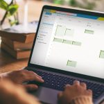 Eine Person blickt auf ein Notebook. Dort ist die Kalenderansicht von Microsoft Outlook ge&ouml;ffnet.