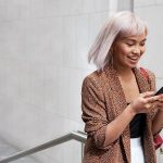 Eine Person l&auml;uft einen Gang entlang und schaut dabei auf ihr Google Pixel 5.