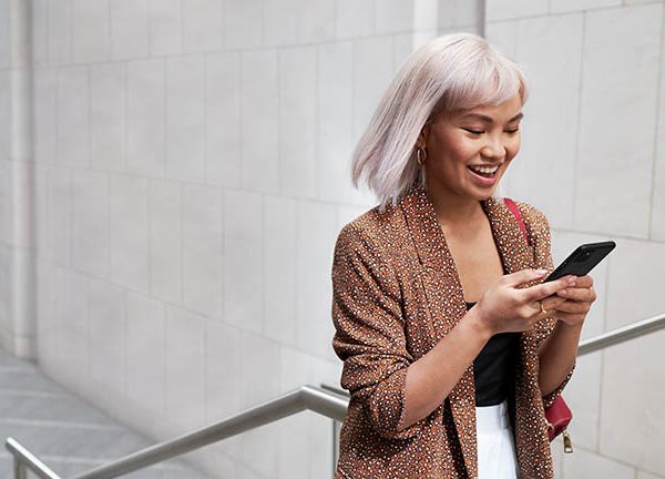 Eine Person l&auml;uft einen Gang entlang und schaut dabei auf ihr Google Pixel 5.
