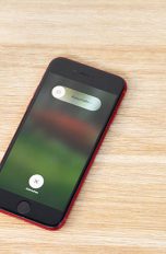 iPhone SE Das iPhone SE liegt auf einem Tisch. Auf dem Display ist der Bildschirm zum Ausschalten des Geräts zu sehen.
